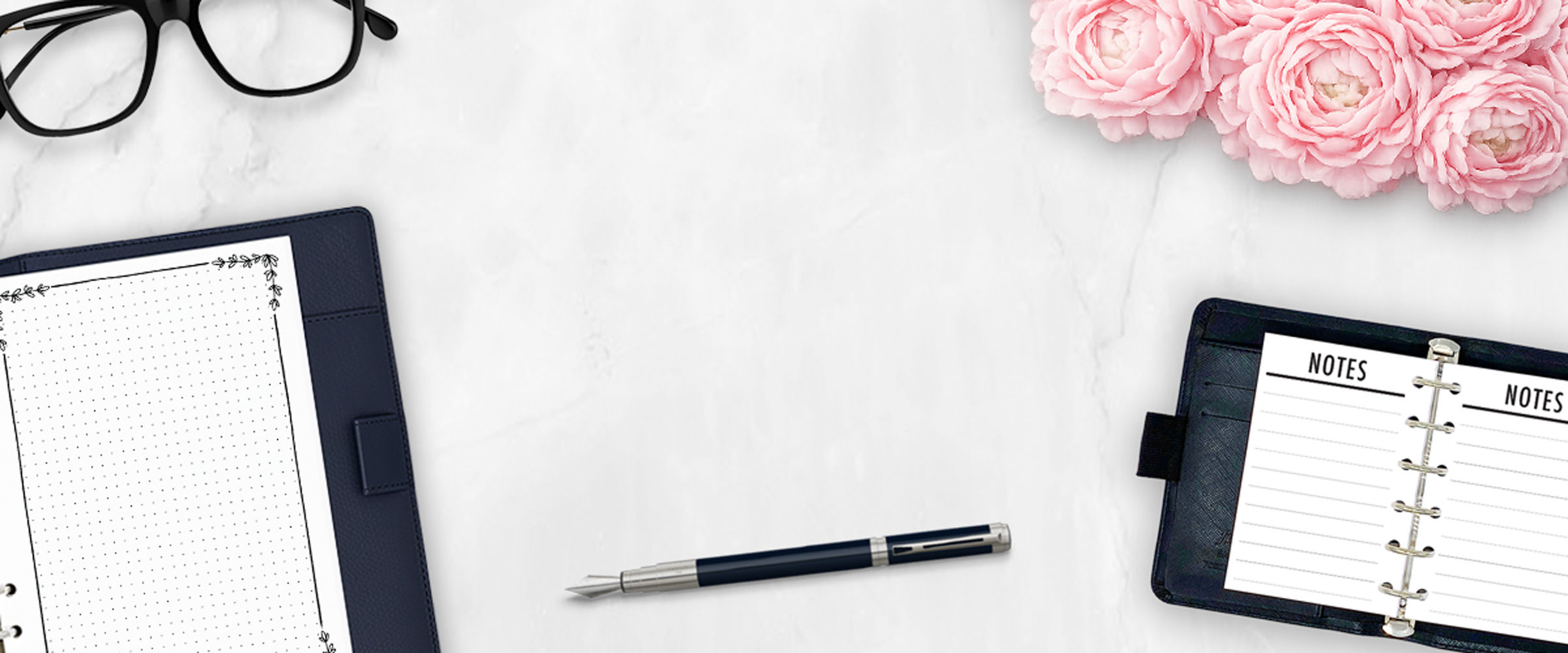 Planner inserts and notebooks on a marble desk