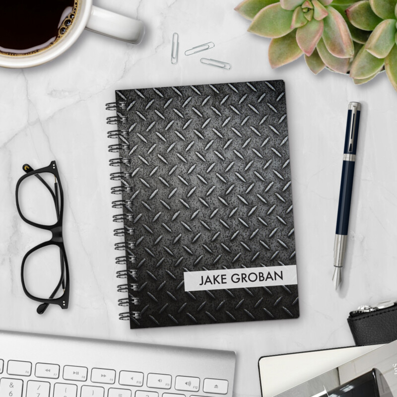 Personalized hardcover notebook in Industrial Strength design with black diamond plate metal pattern styled on marble desk with coffee, glasses, and pen