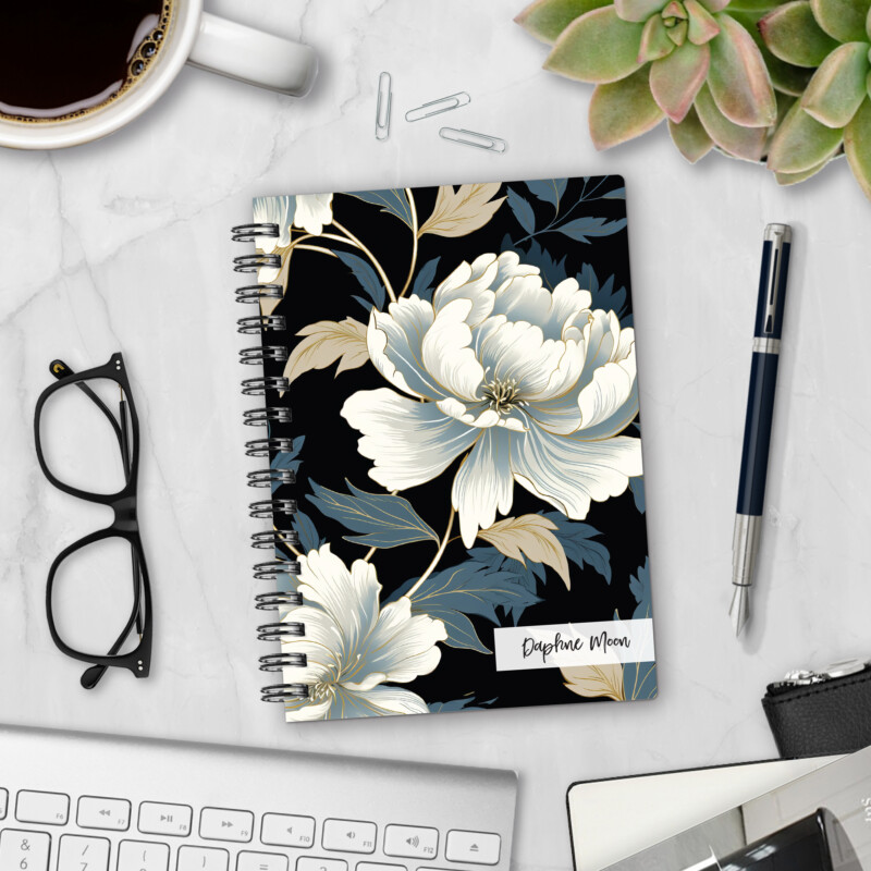 Personalized hardcover notebook in Midnight Bloom design with elegant white peonies and gold accents on black background styled on marble desk with pen