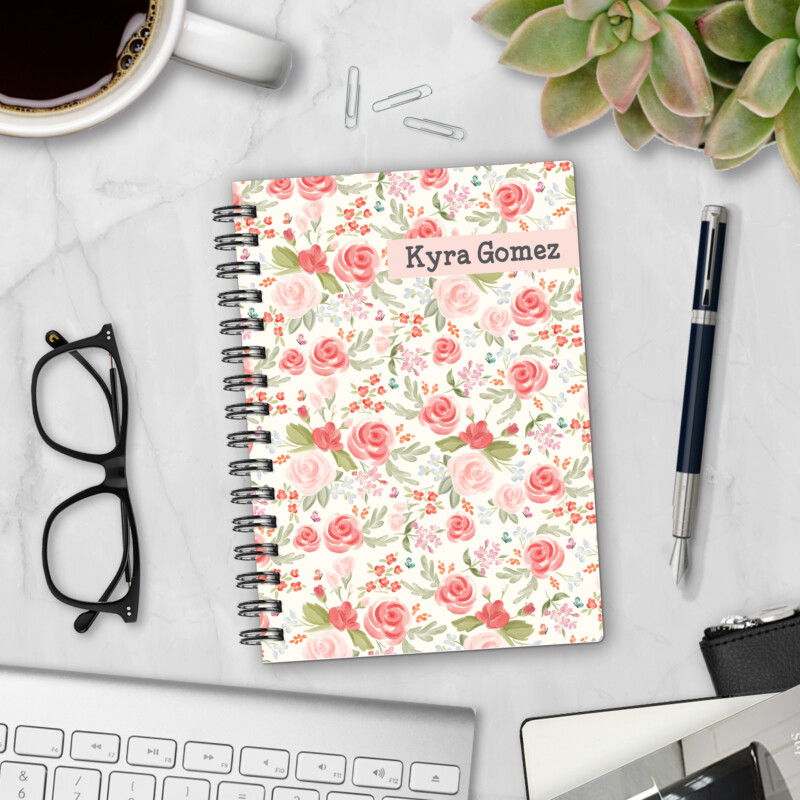 Personalized hardcover notebook in Quiet Garden design with watercolor pink roses and soft floral pattern on cream background styled on marble desk