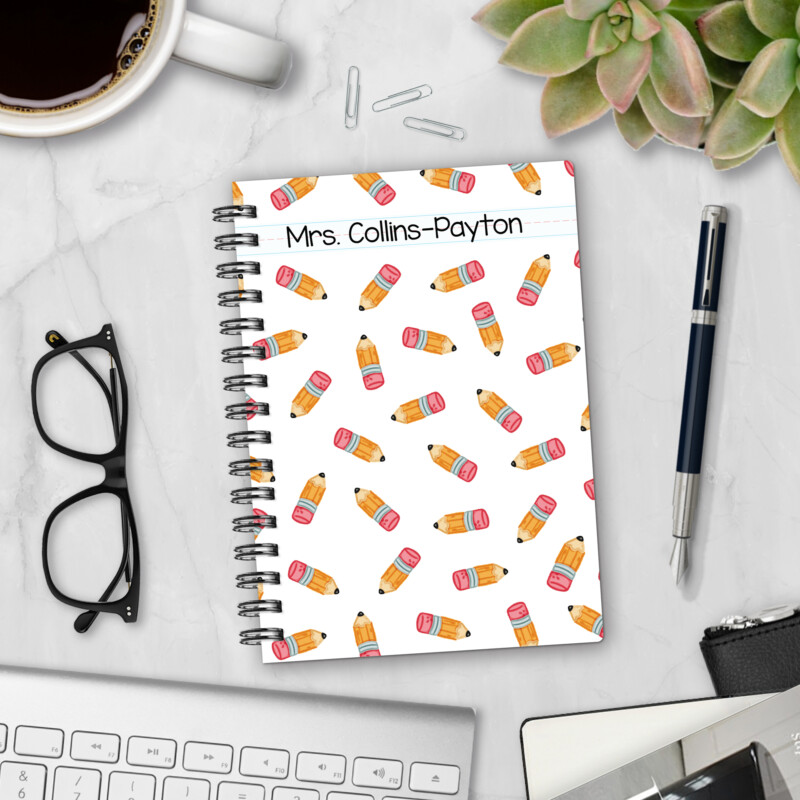 Personalized hardcover notebook in Sharpened Pencils design with scattered yellow pencils on white background and primary lined name banner styled with pen