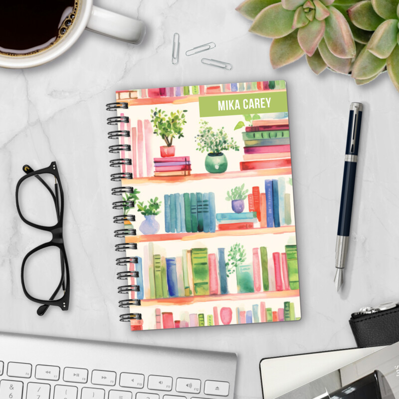 Personalized hardcover notebook in Shelf Control design with watercolor bookshelves filled with colorful books and plants styled on marble desk with coffee