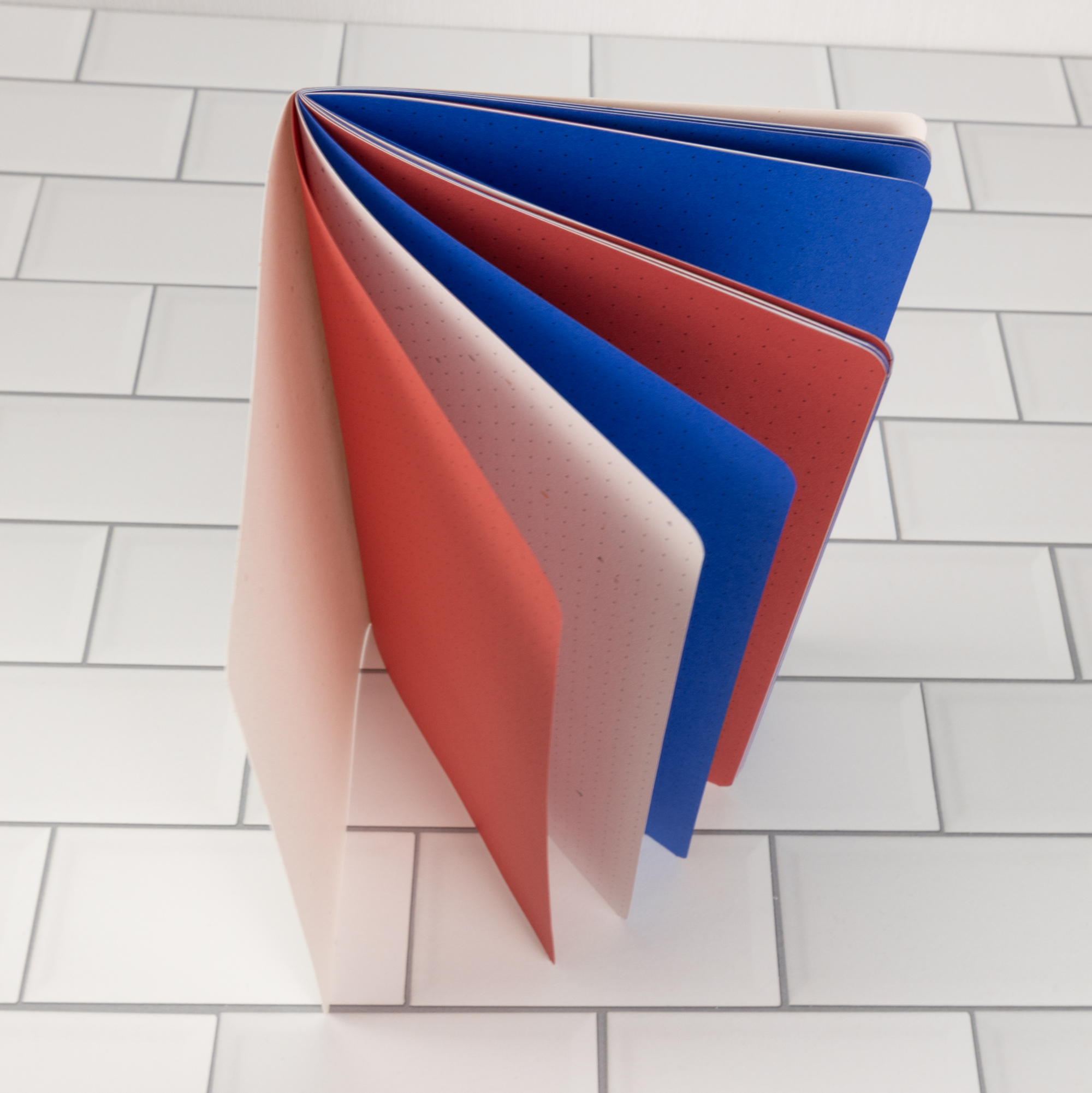 Firecracker traveler's notebook insert standing upright fanned open showing patriotic red, speckled white, and blue pages.