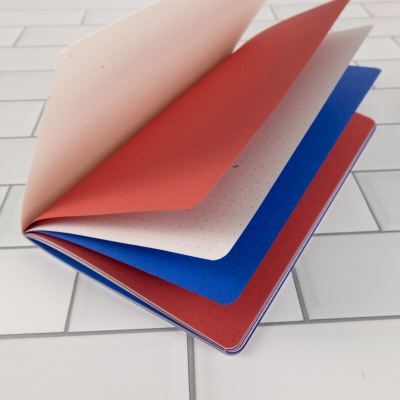 Firecracker traveler's notebook insert fanned open showing patriotic red, speckled white, and blue layered pages.