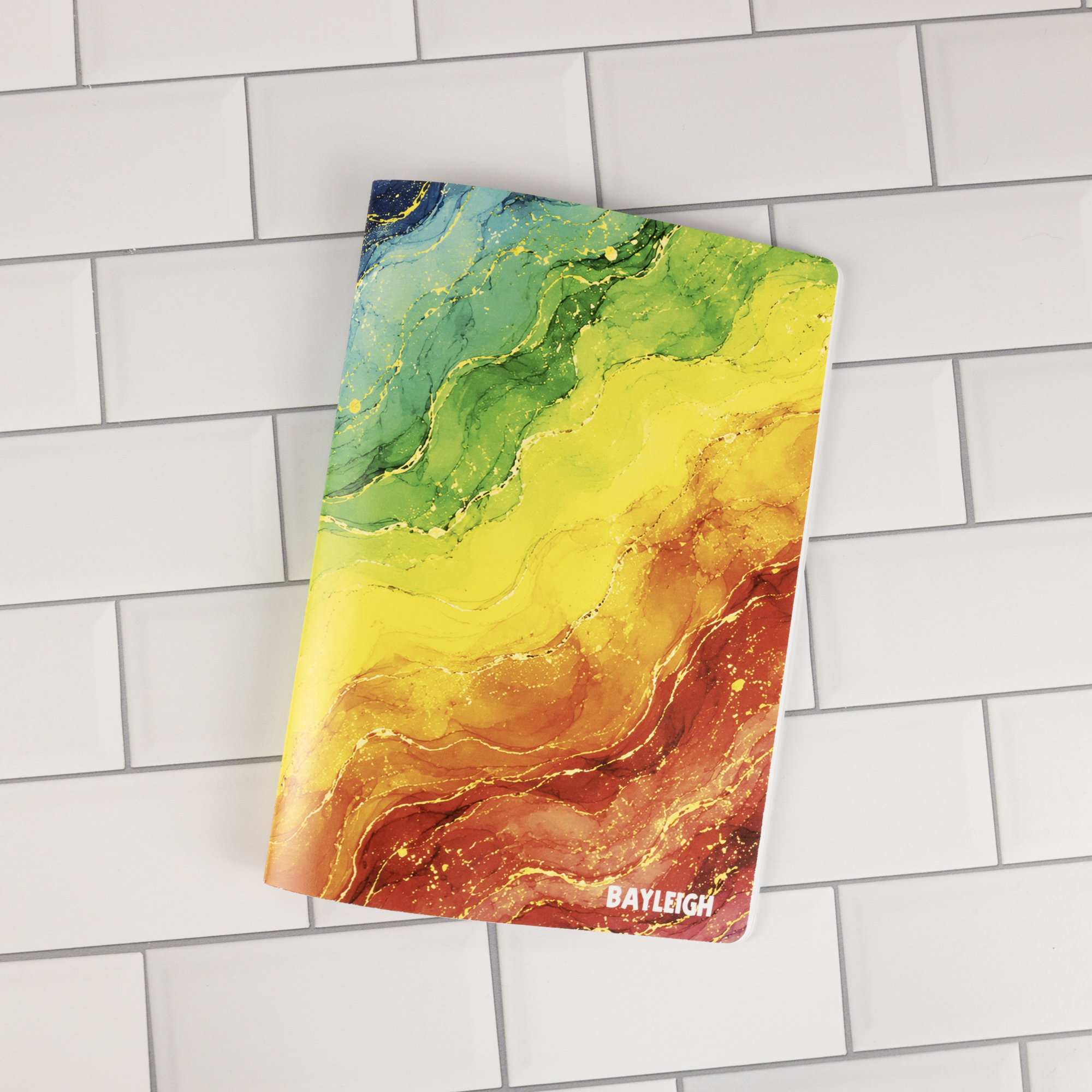 Prism personalized traveler's notebook insert open showing rainbow watercolor marble cover lifted, revealing white pages with rainbow-colored ruled lines.