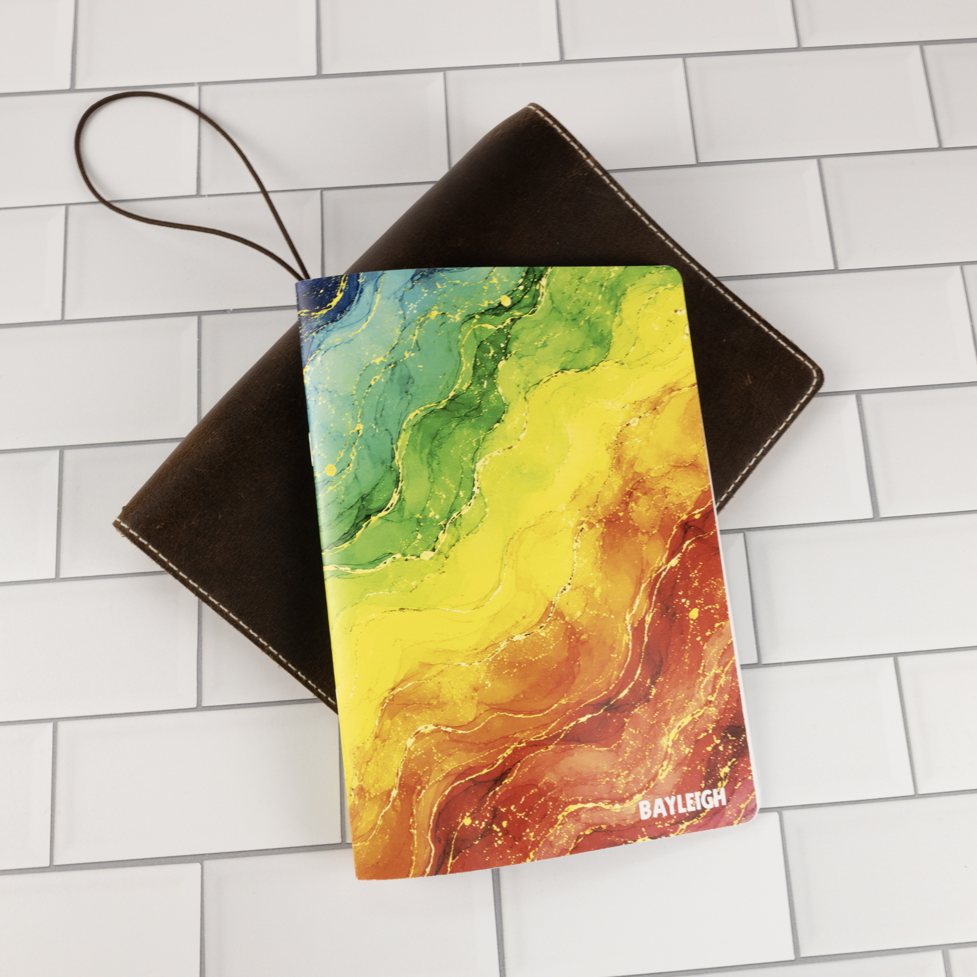 Prism personalized traveler's notebook insert flat-lay showing closed rainbow watercolor marble cover with personalized name in white.