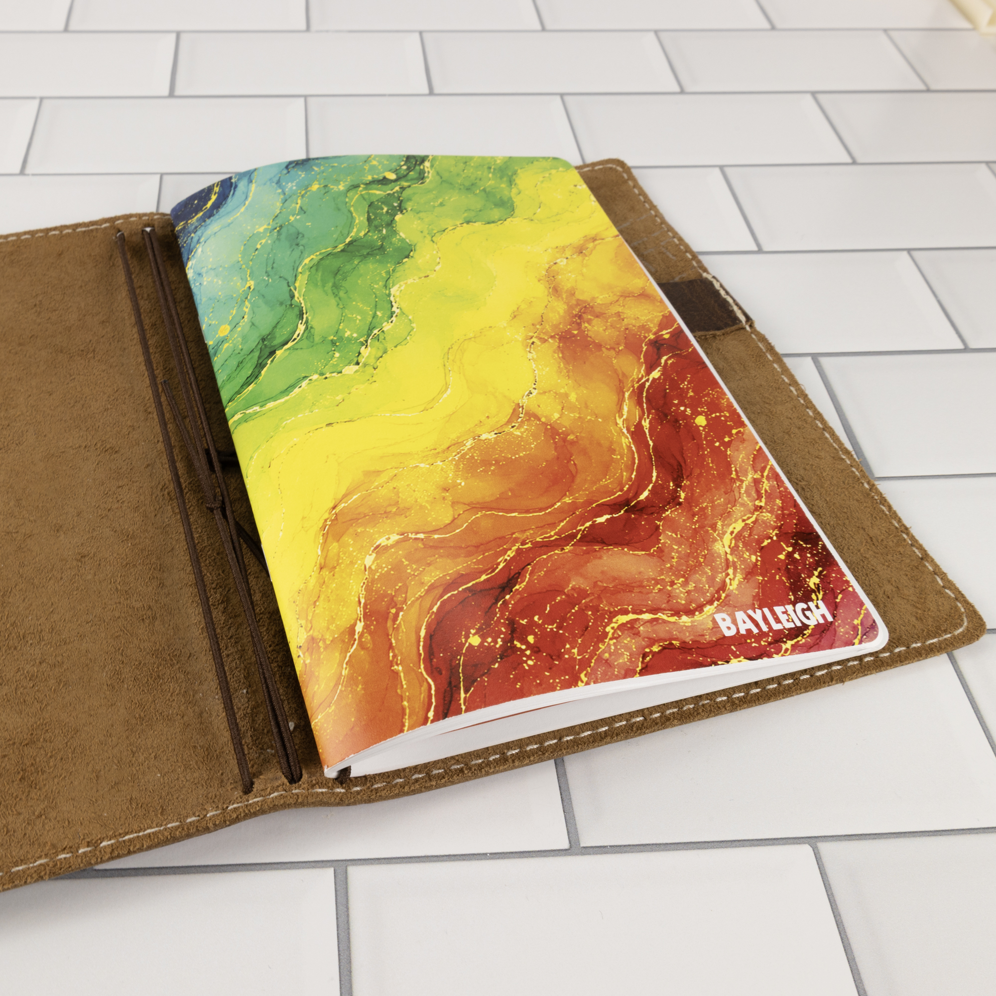 Prism personalized traveler's notebook insert shown inside a tan leather traveler's notebook binder, cover visible at angle.