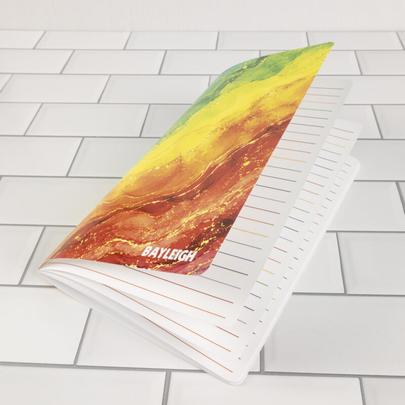 Prism personalized traveler's notebook insert open showing rainbow watercolor marble cover and white pages with rainbow-colored ruled lines.