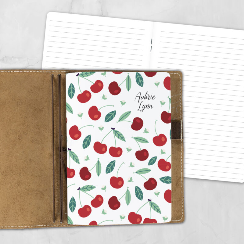 A5 Cherry Sweet personalized traveler's notebook refill showing the cover design inside a leather traveler's notebook cover, with lined refill pages visible behind.
