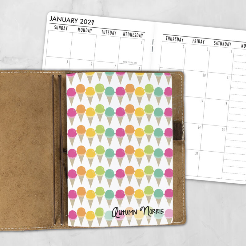 A5 Cone Zone personalized traveler's notebook refill showing the cover design inside a leather traveler's notebook cover, with a monthly calendar spread visible behind.