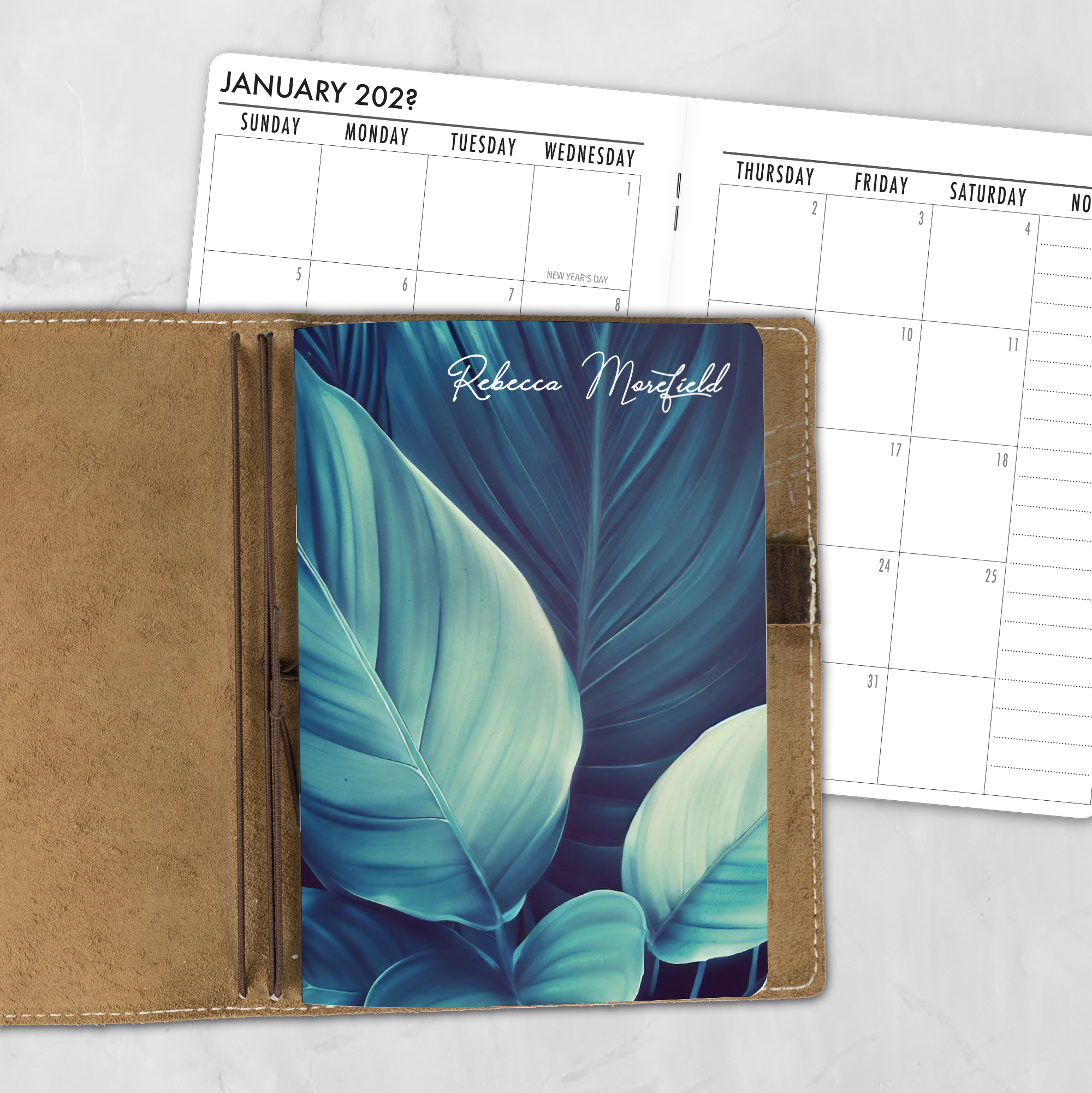 A5 Dark Forest lifestyle personalized traveler's notebook refill showing the cover design inside a leather traveler's notebook cover, with a monthly calendar spread visible behind.