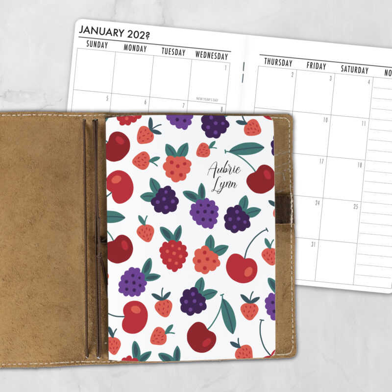 A5 Jam Session personalized traveler's notebook refill showing the cover design inside a leather traveler's notebook cover, with a monthly calendar spread visible behind.