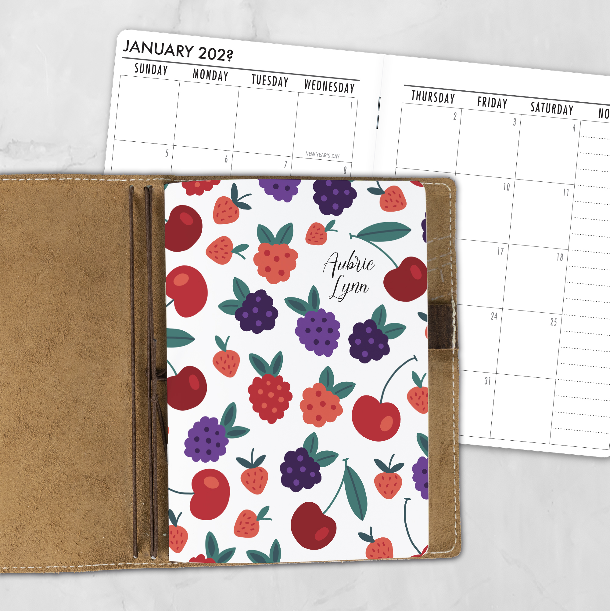 A5 Jam Session personalized traveler's notebook refill showing the cover design inside a leather traveler's notebook cover, with a monthly calendar spread visible behind.