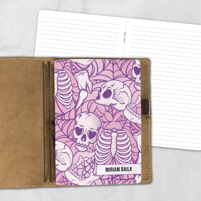 A5 Lovesick Bones lifestyle personalized traveler's notebook refill showing the cover design inside a leather traveler's notebook cover, with lined refill pages visible behind.