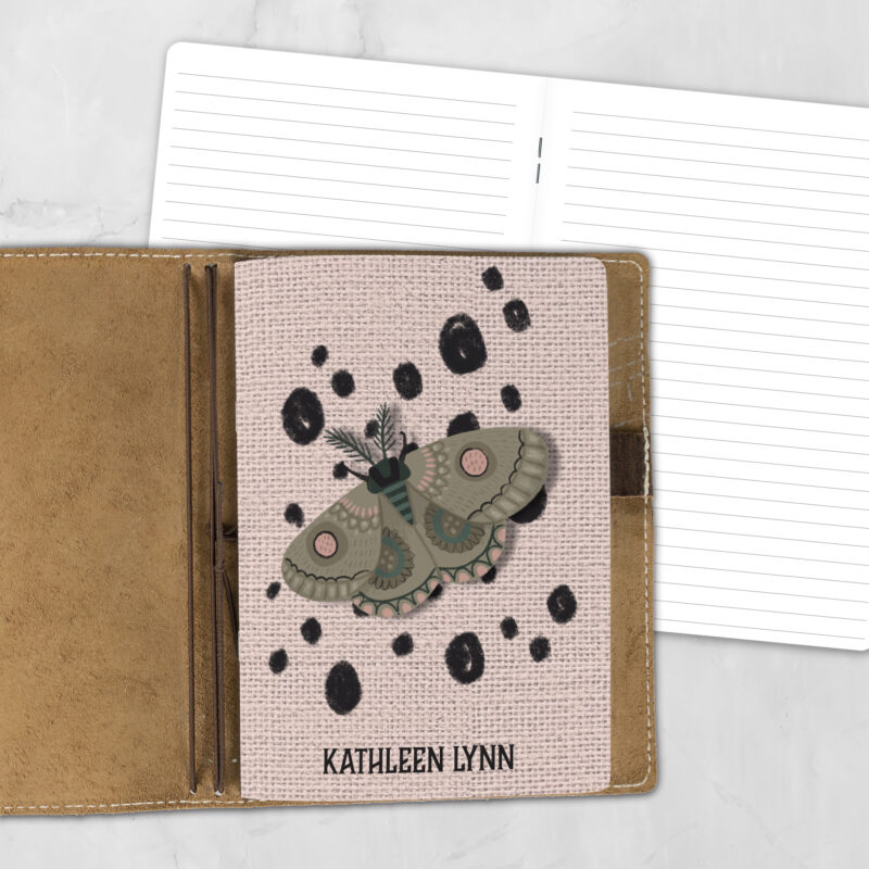 A5 Moth Dust Dot personalized traveler's notebook refill showing the cover design inside a leather traveler's notebook cover, with lined refill pages visible behind.