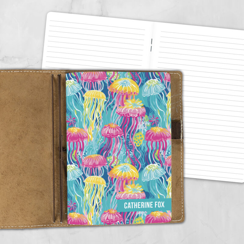A5 Neon Jellyfish personalized traveler's notebook refill showing the cover design inside a leather traveler's notebook cover, with lined refill pages visible behind.