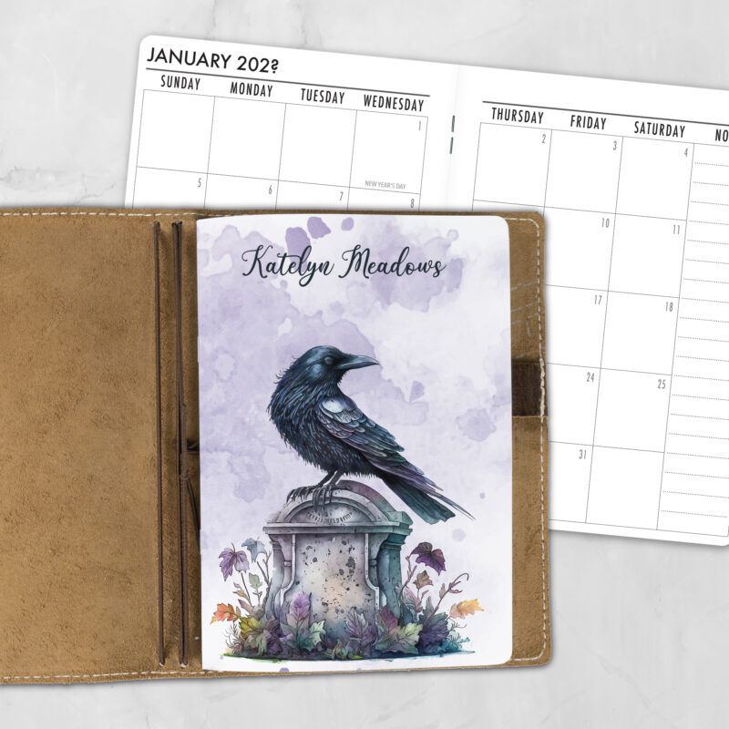 A5 Nevermore personalized traveler's notebook refill showing the cover design inside a leather traveler's notebook cover, with a monthly calendar spread visible behind.