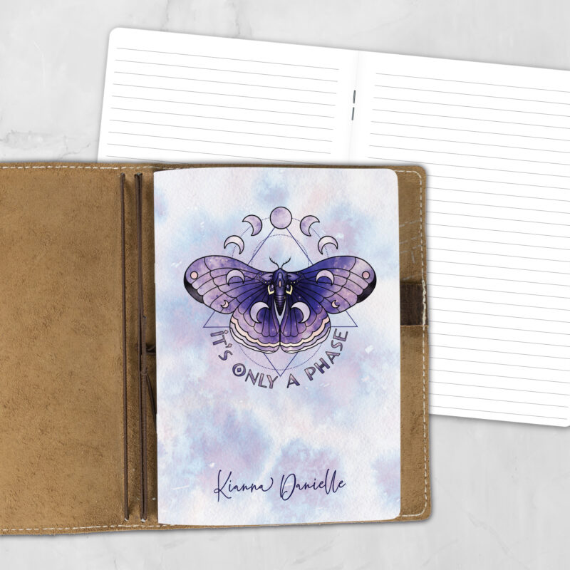 A5 Only a Phase personalized traveler's notebook refill showing the cover design inside a leather traveler's notebook cover, with lined refill pages visible behind.