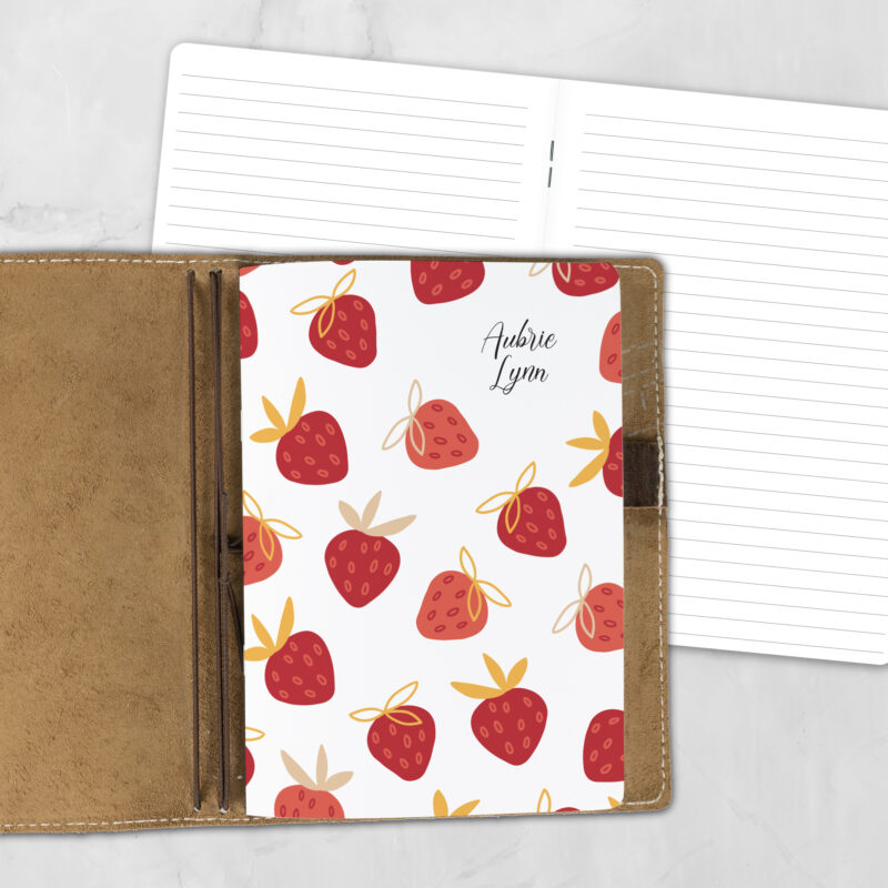 A5 Strawberry Crush personalized traveler's notebook refill showing the cover design inside a leather traveler's notebook cover, with lined refill pages visible behind.