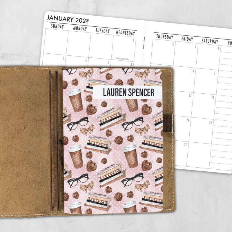A5 The Brew Review personalized traveler's notebook refill showing the cover design inside a leather traveler's notebook cover, with a monthly calendar spread visible behind.