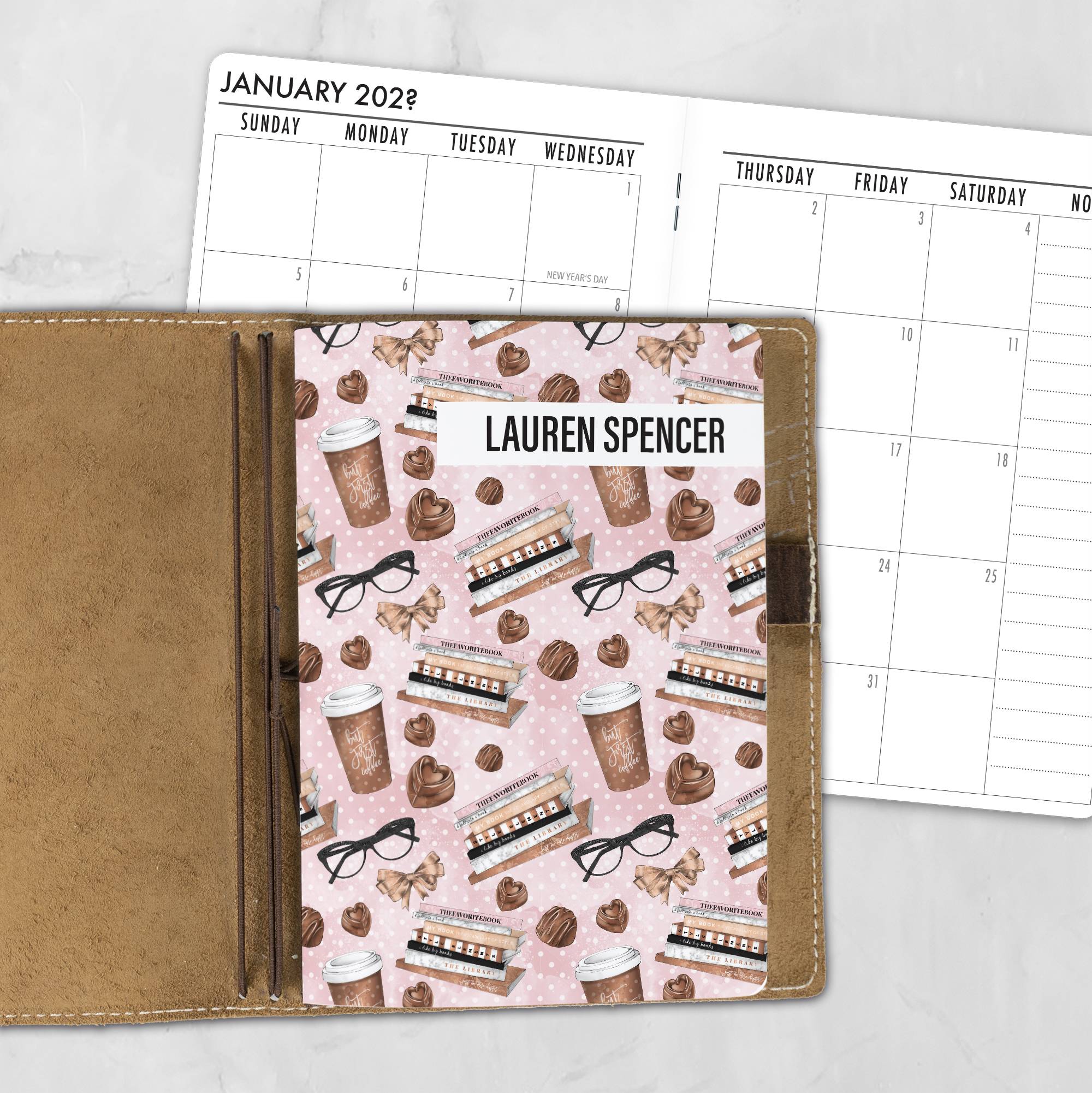 A5 The Brew Review personalized traveler's notebook refill showing the cover design inside a leather traveler's notebook cover, with a monthly calendar spread visible behind.