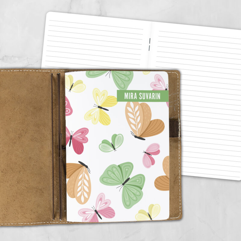 A5 Whimsical Wings personalized traveler's notebook refill showing the cover design inside a leather traveler's notebook cover, with lined refill pages visible behind.