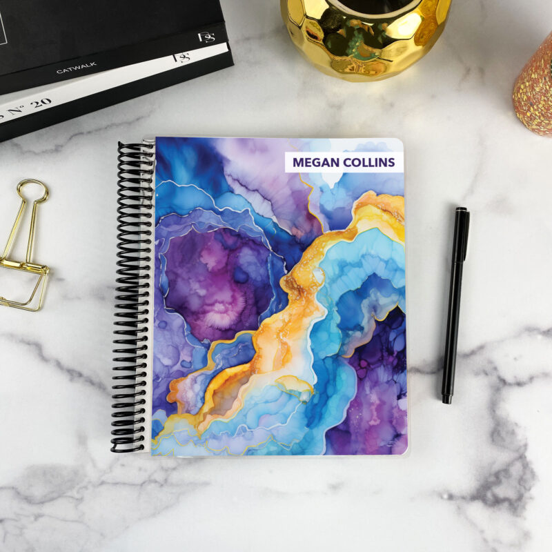 7x9 spiral bound planner in the Amethyst Geode cover design on a marble surface with styling accessories.