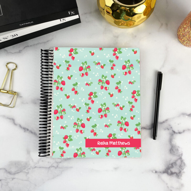 7x9 spiral bound planner in the Berry Overbooked cover design on a marble surface with styling accessories.