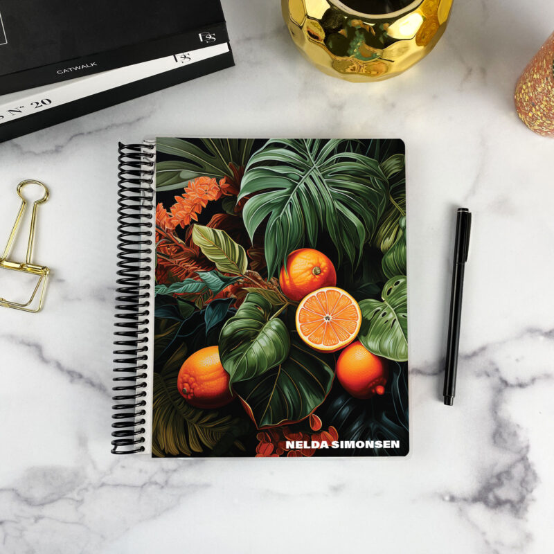 7x9 spiral bound planner in the Blood Orange cover design on a marble surface with styling accessories.