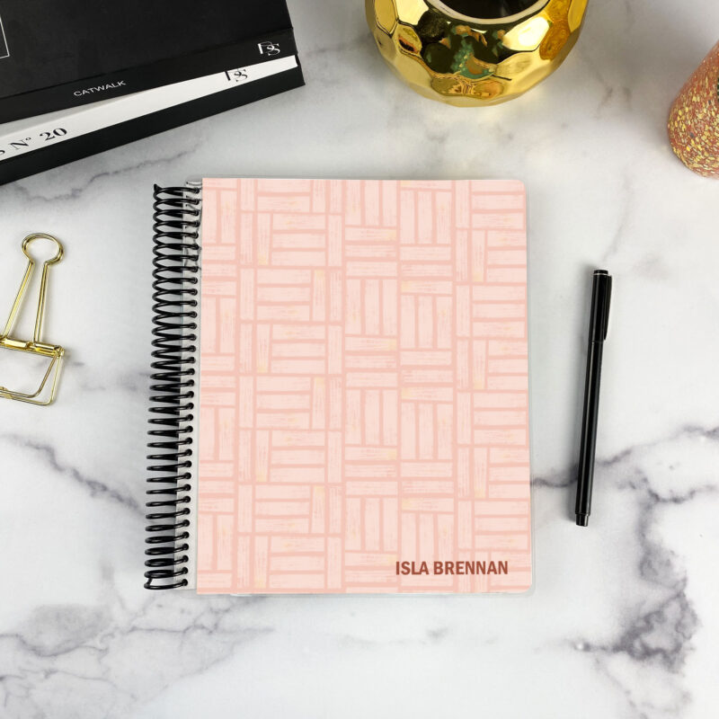 7x9 spiral bound planner in the Blush Basketweave cover design on a marble surface with styling accessories.
