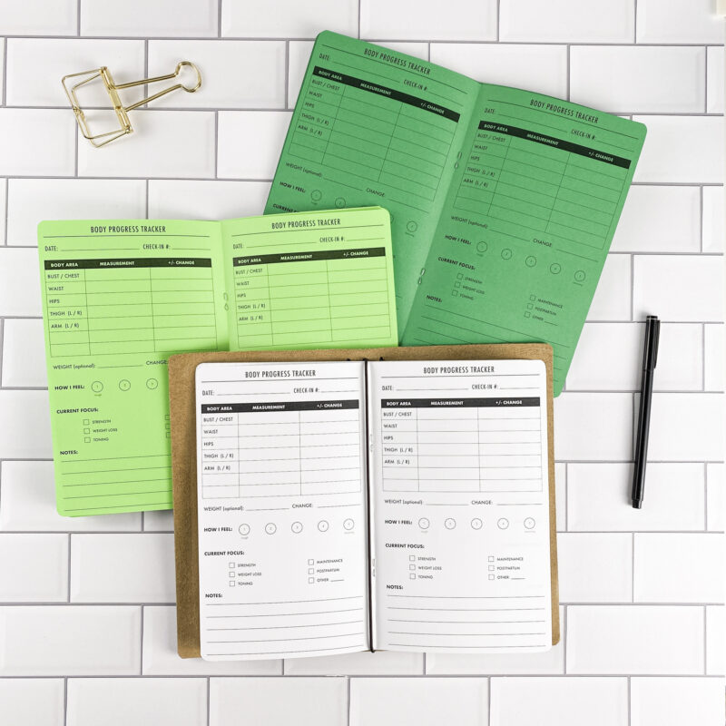 Body Progress traveler's notebook refill by CityGirl Planners, showing body measurement and progress tracking pages. Three booklets displayed in different paper color options inside a traveler's notebook cover.