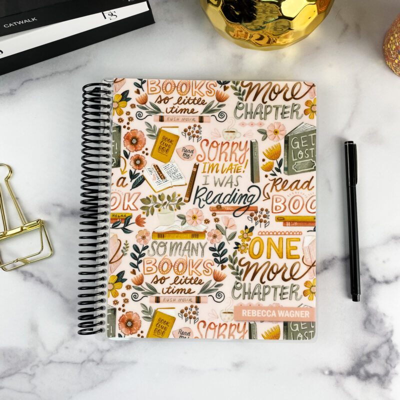 7x9 spiral bound planner in the Bookworm's Delight cover design on a marble surface with styling accessories.