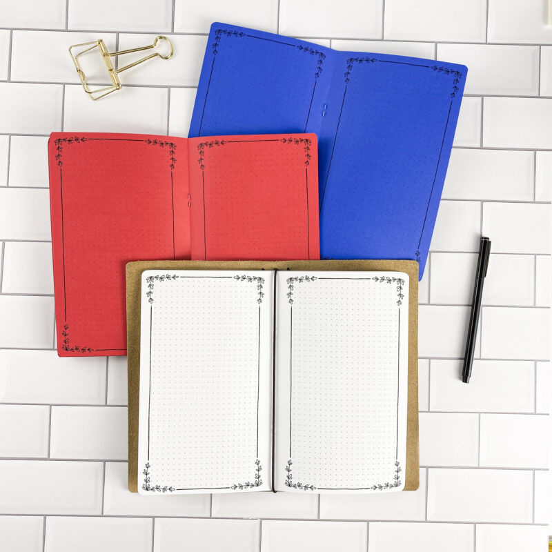Botanical Notes traveler's notebook refill by CityGirl Planners, showing decorative note pages with botanical floral border design. Three booklets displayed in different paper color options inside a traveler's notebook cover.
