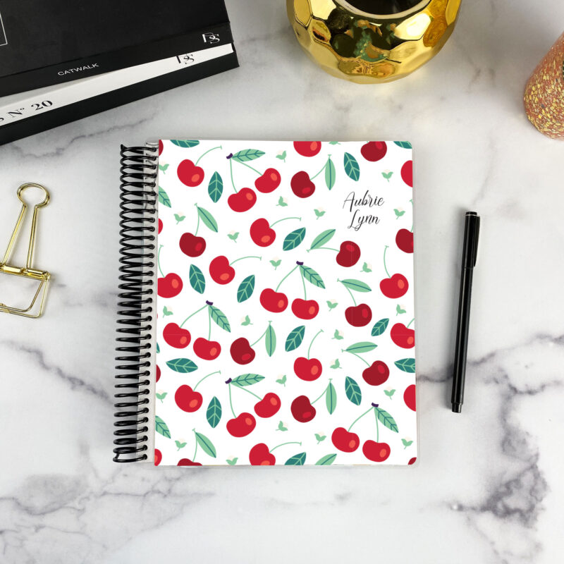7x9 spiral bound planner in the Cherry Sweet cover design on a marble surface with styling accessories.