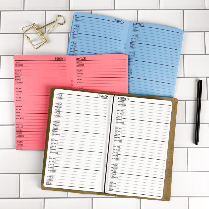 Contacts traveler's notebook refill by CityGirl Planners, showing contacts and address book pages. Three booklets displayed in different paper color options inside a traveler's notebook cover.