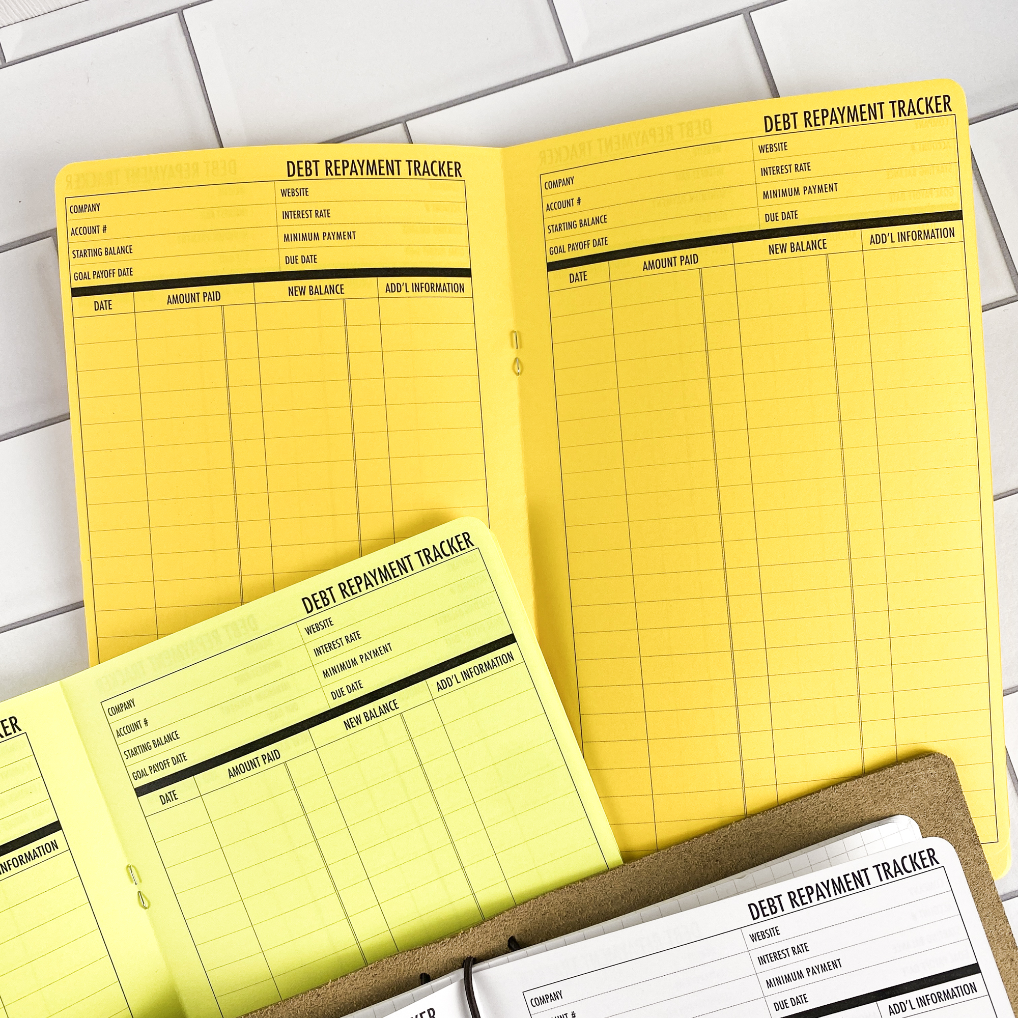 Detail view of the Debt Repayment traveler's notebook refill showing debt repayment tracker pages for managing payoff progress, displayed with multiple paper color options.