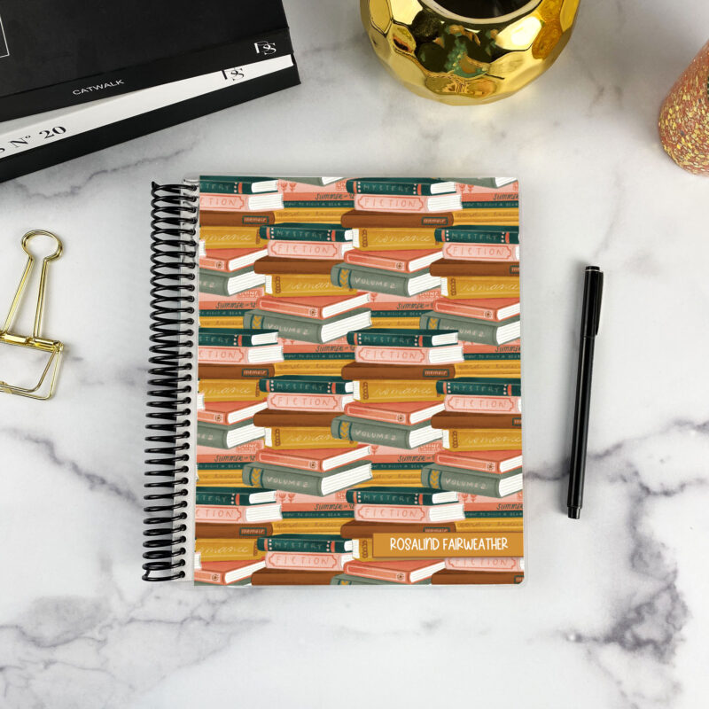 7x9 spiral bound planner in the Genre Stacks cover design on a marble surface with styling accessories.