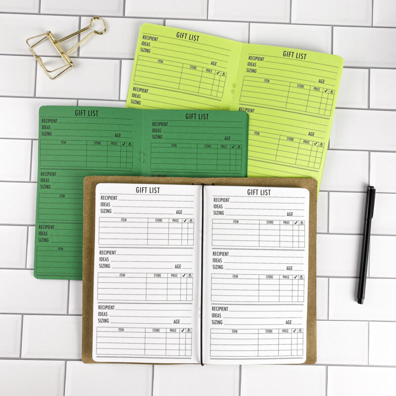 Gift List traveler's notebook refill by CityGirl Planners, showing gift list planning pages for tracking gift ideas and budgets. Three booklets displayed in different paper color options inside a traveler's notebook cover.