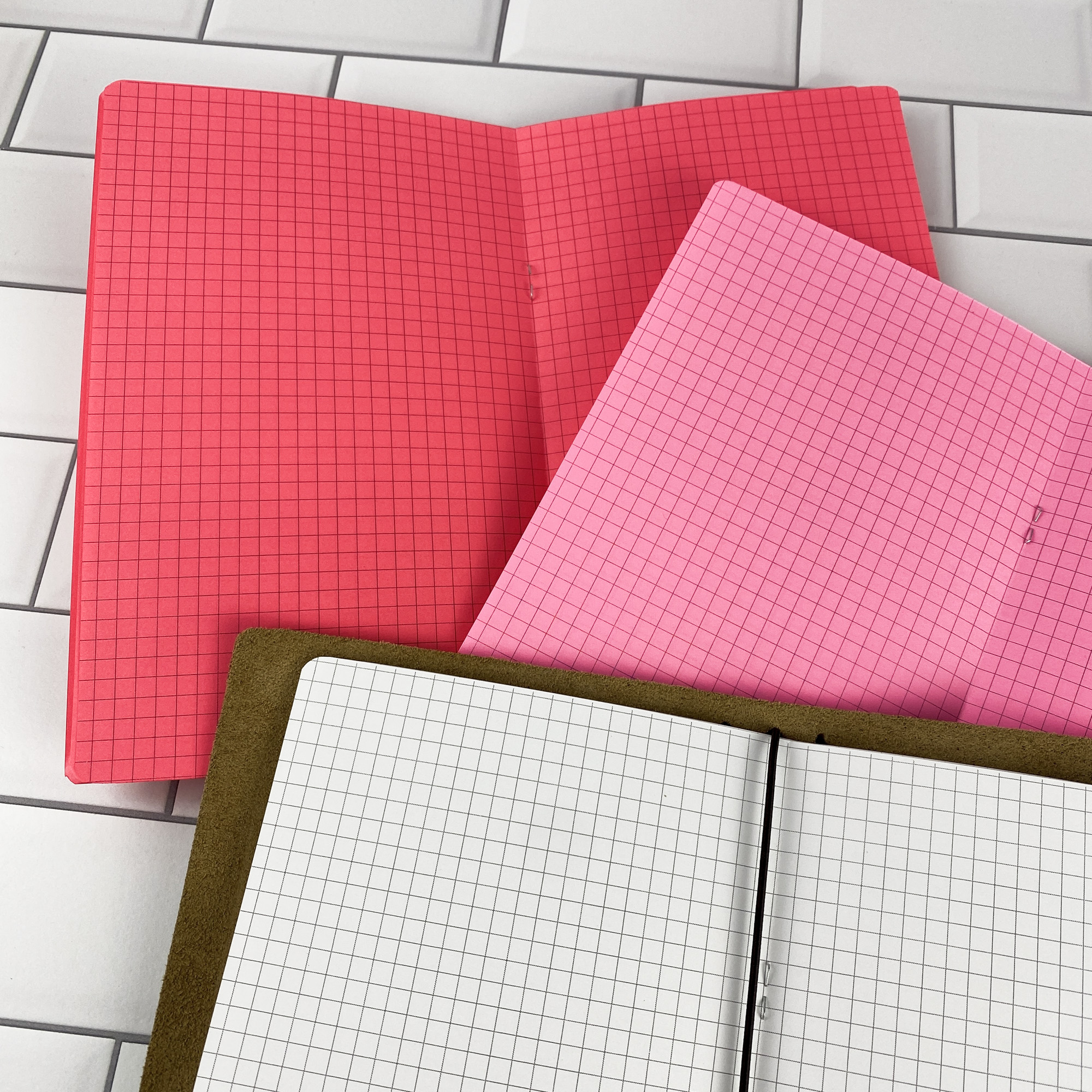 Detail view of the Graph Paper traveler's notebook refill showing graph paper grid pages, displayed with multiple paper color options.