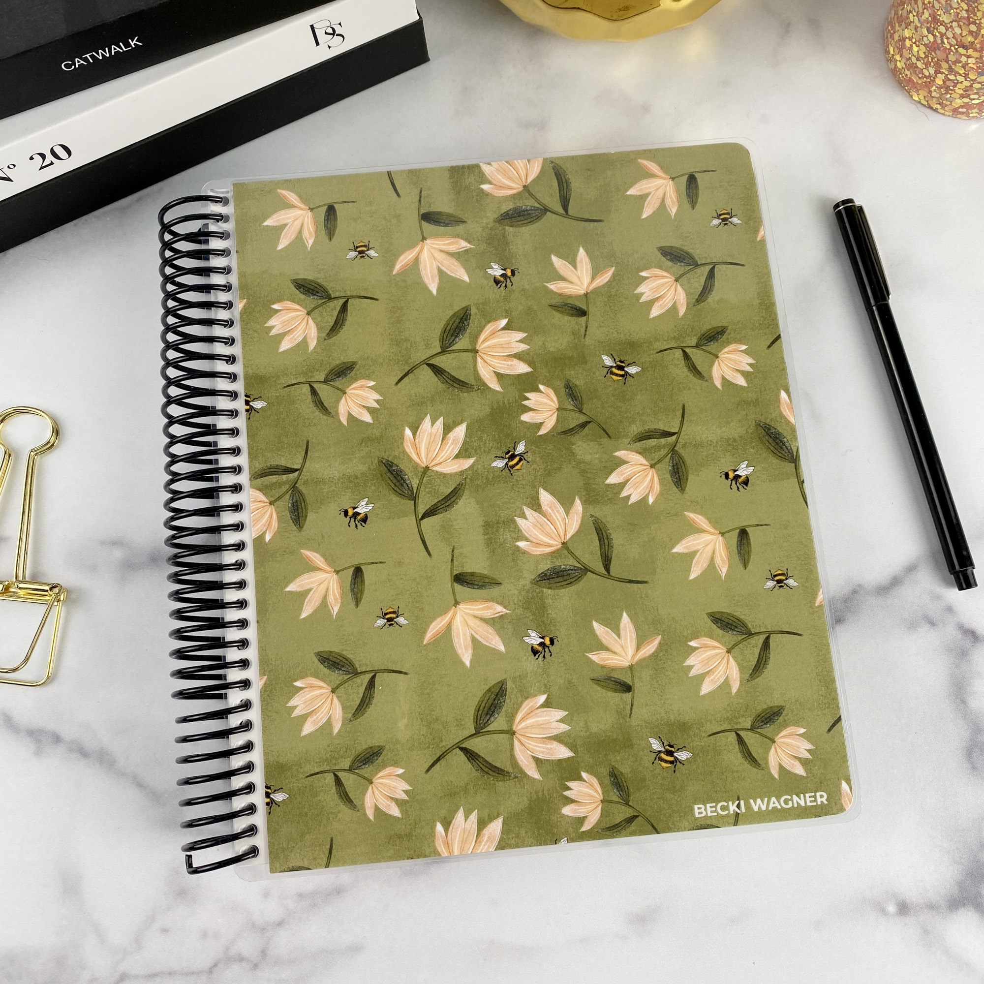 7x9 spiral bound planner in the Honey Blossom cover design on a marble surface with styling accessories.