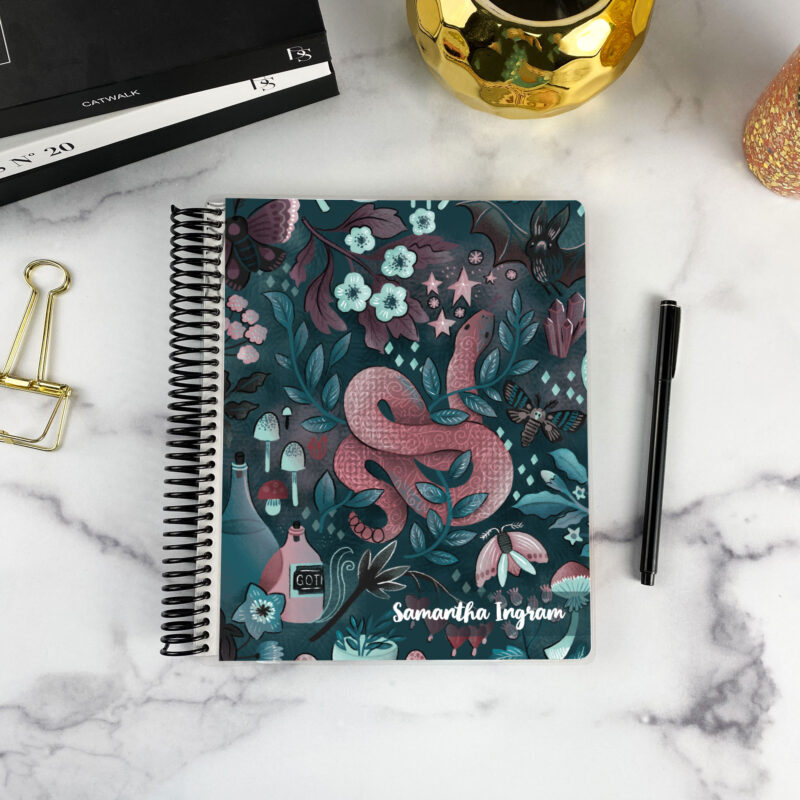 7x9 spiral bound planner in the Into the night cover design on a marble surface with styling accessories.