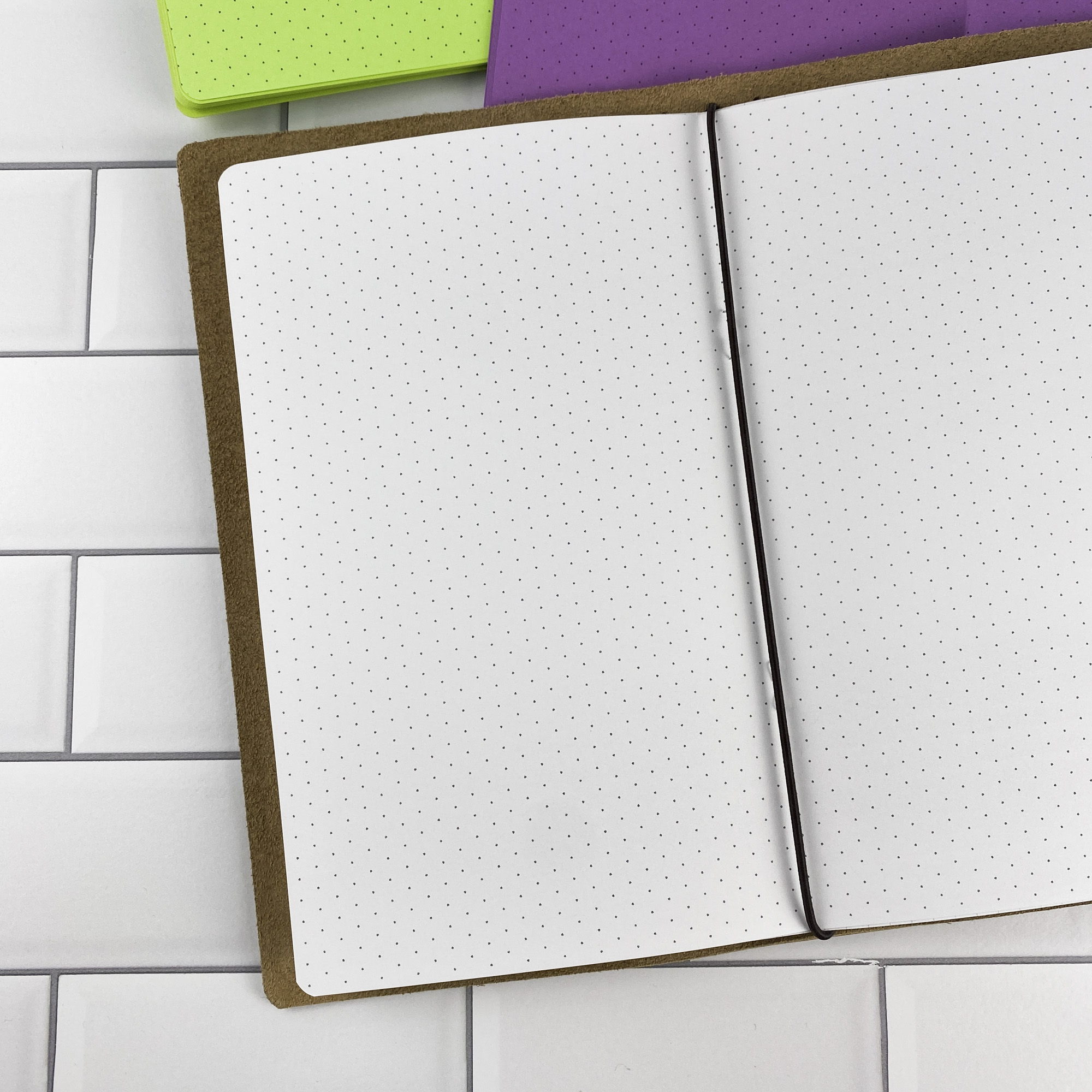 Detail view of the Isometric Dots traveler's notebook refill showing isometric dot grid pages for 3D sketching and technical drawing, displayed with multiple paper color options.