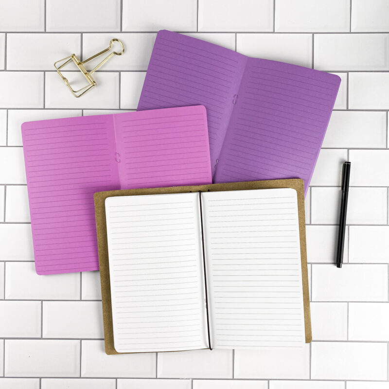 Lined traveler's notebook refill by CityGirl Planners, showing lined pages for everyday note taking. Three booklets displayed in different paper color options inside a traveler's notebook cover.