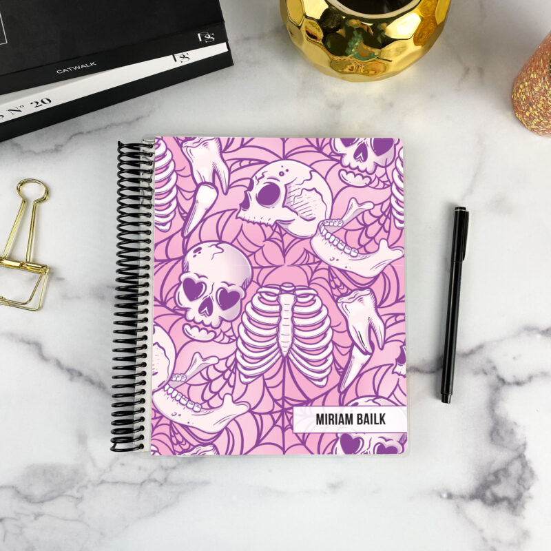 7x9 spiral bound planner in the Lovesick Bones cover design on a marble surface with styling accessories.