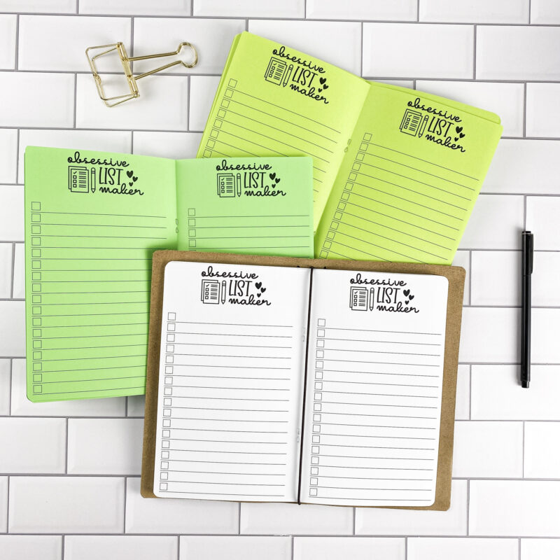 Obsessive List Maker traveler's notebook refill by CityGirl Planners, showing list-making pages with a fun header design for organizing everything. Three booklets displayed in different paper color options inside a traveler's notebook cover.