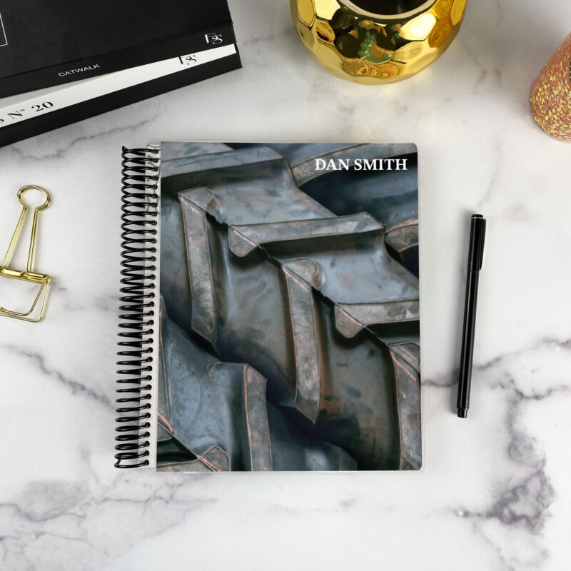 7x9 spiral bound planner in the Off-Road Agenda cover design on a marble surface with styling accessories.
