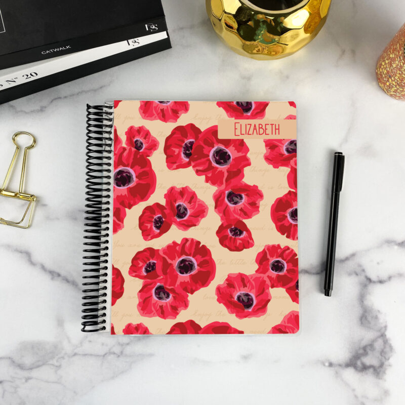 7x9 spiral bound planner in the Poppy Prose cover design on a marble surface with styling accessories.