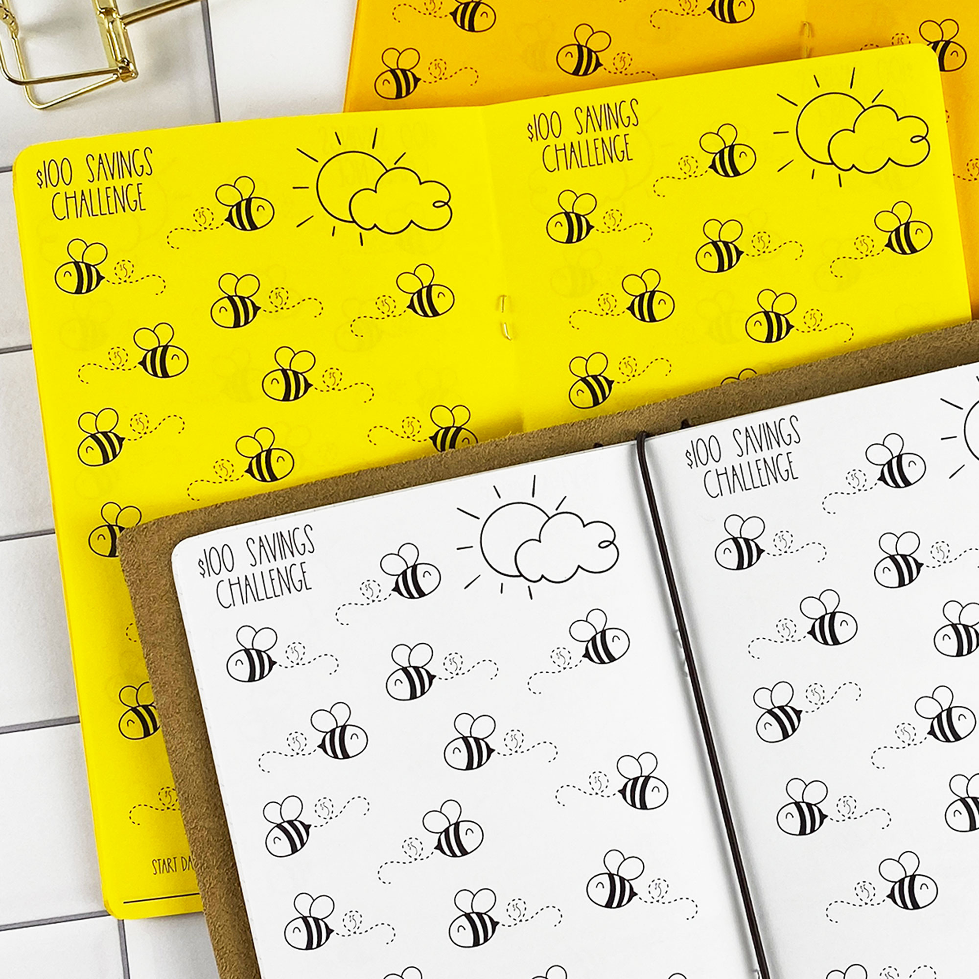 Close-up detail of the Savings Challenge Buzzin Bees traveler's notebook refill showing the page layout and $100 savings challenge pages with cute bee illustrations to color in as you save in colored paper.