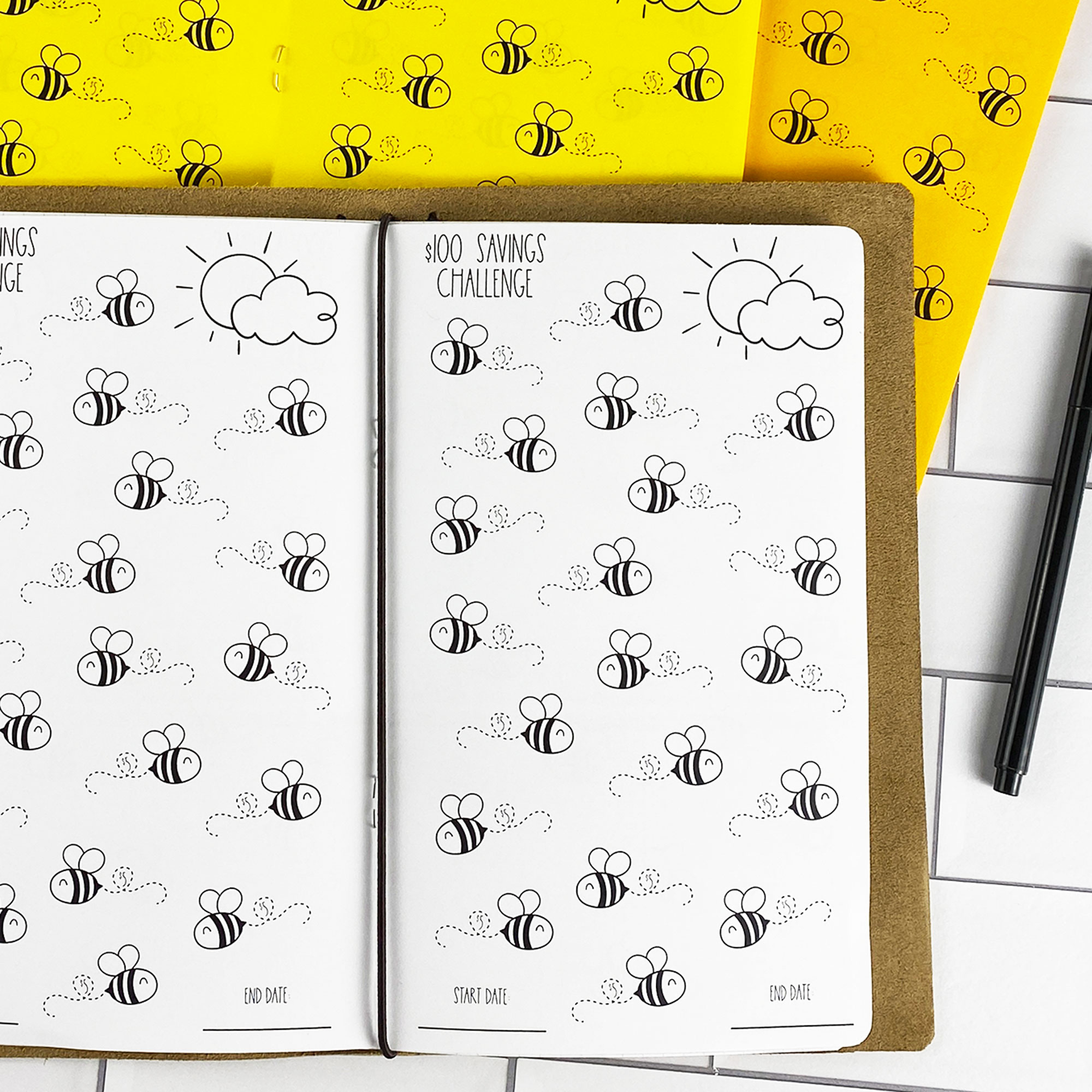 Detail view of the Savings Challenge Buzzin Bees traveler's notebook refill showing $100 savings challenge pages with cute bee illustrations to color in as you save, displayed with multiple paper color options.