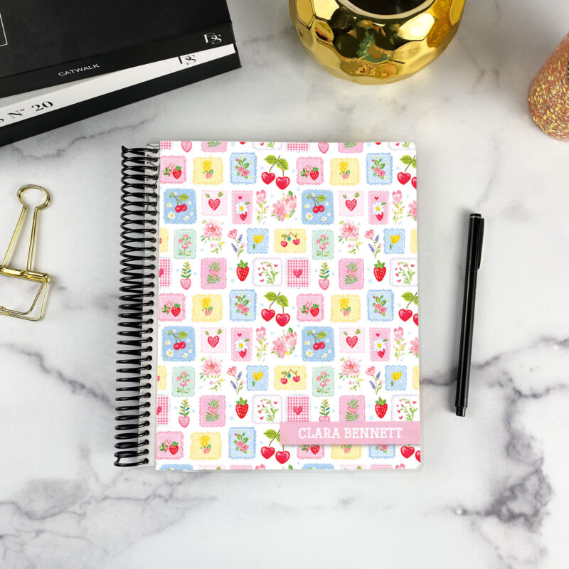 7x9 spiral bound planner in the Sweetheart Stamps cover design on a marble surface with styling accessories.